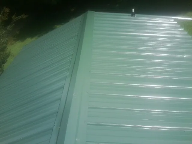 New green metal panels meeting at the ridge of a roof — Flat Roof Repair work by our crew in Port Edwards