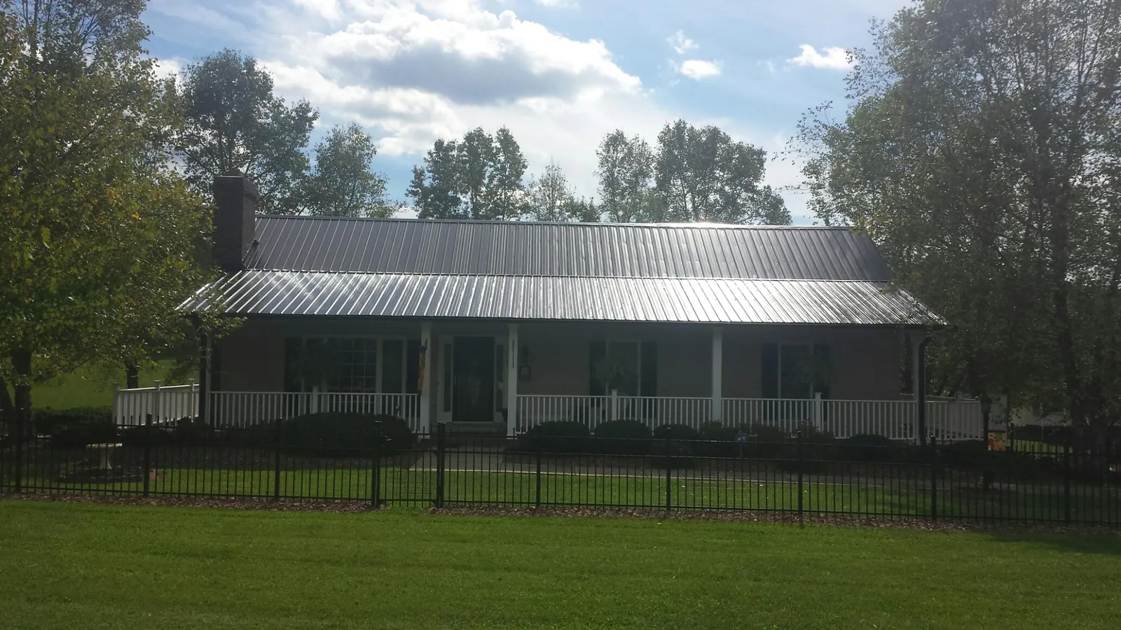 Gray metal roof on a brick ranch with a full width front porch — Gutter Guard Installation work by our crew in Port Edwards