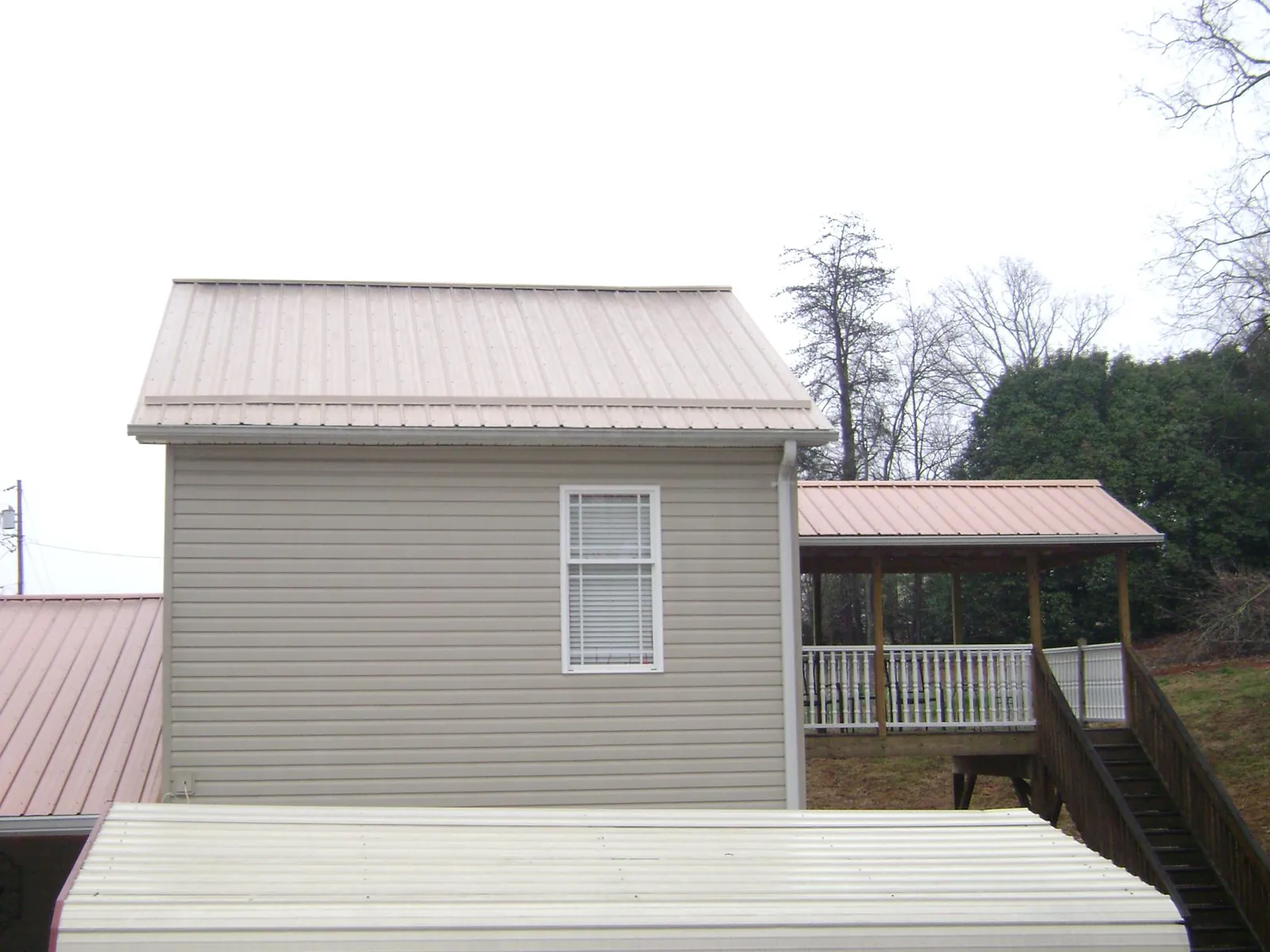 Tan metal roofs on a two story addition and attached porch, from a Roof Replacement job in Port Edwards