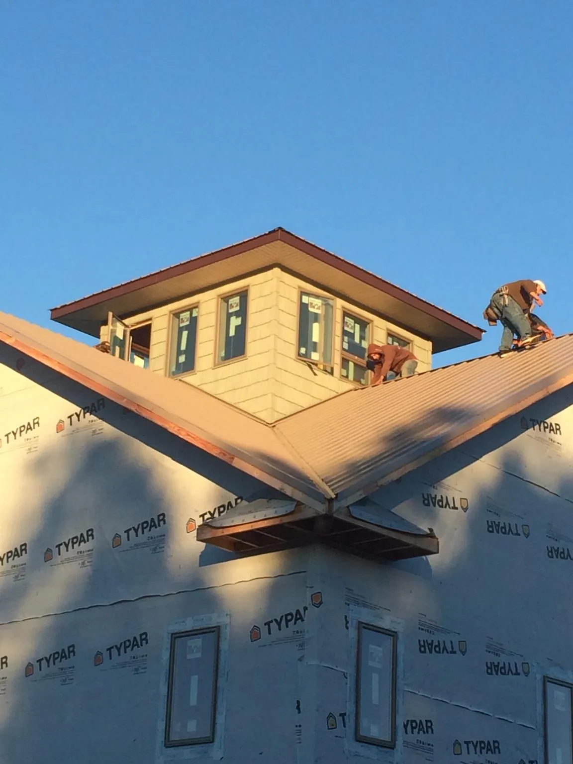 Roofers working around a rooftop cupola on a new metal roof at sunset — Roof Waterproofing in Port Edwards by Roofing Brothers